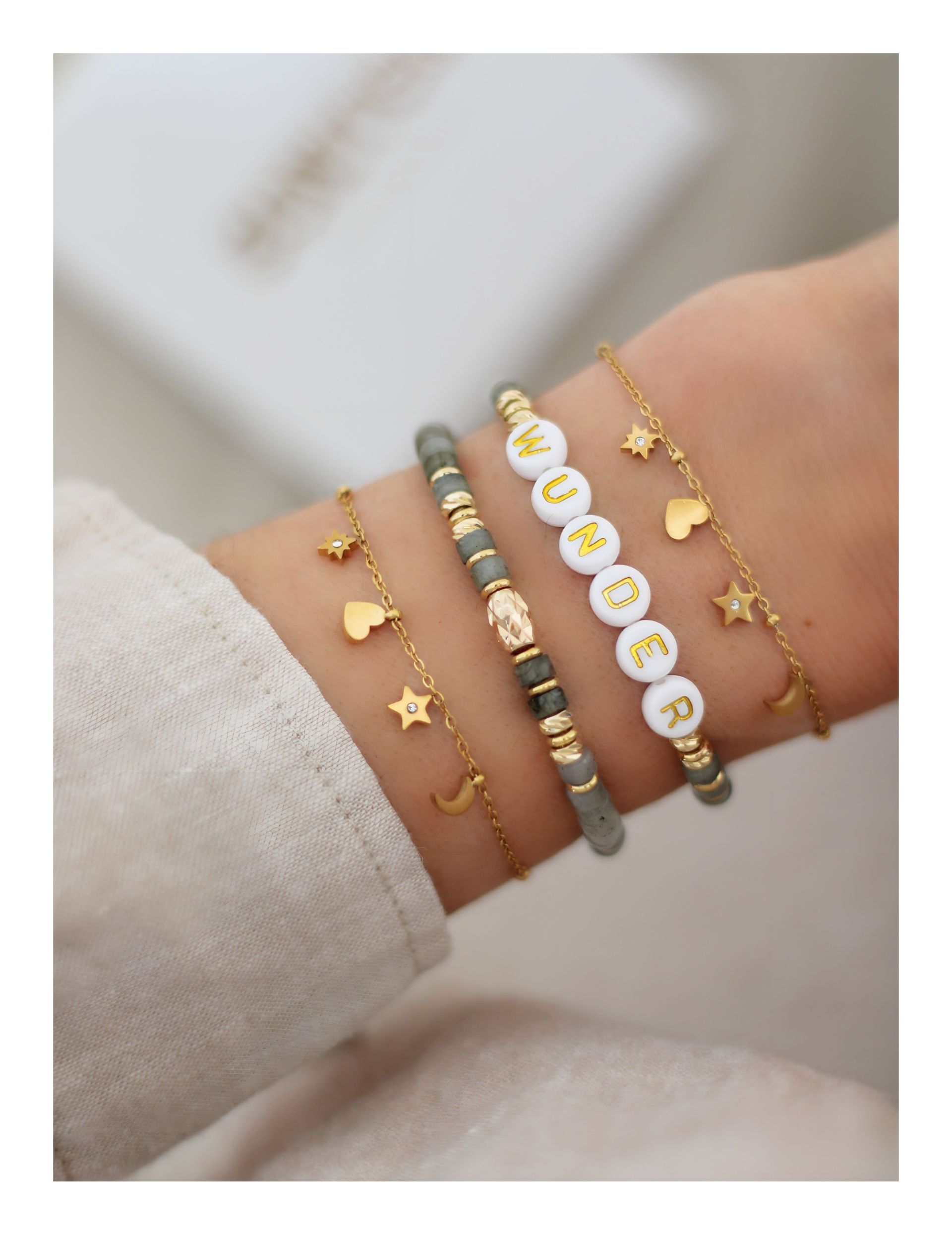 Nahaufnahme eines zarten, goldenen Edelstahl Armbandes mit Herz, Mond und Sternenanhängern. Geschenkidee für Freundin Tochter