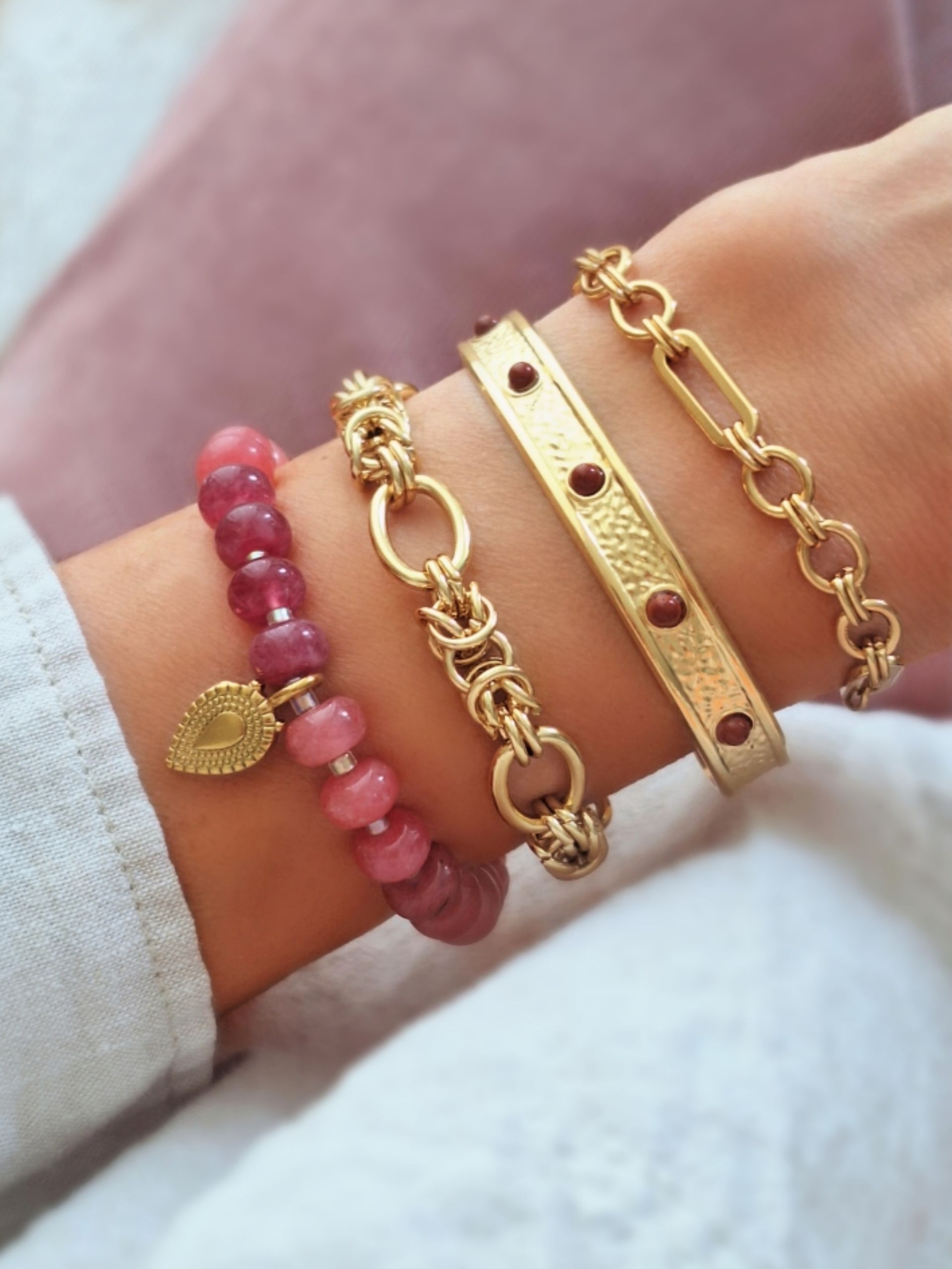 Nahaufnahme eines Goldenen Manschetten-Armreif verziert mit hübschen, roten Schmucksteinen. Perfekt für Urlaub und Sommer 