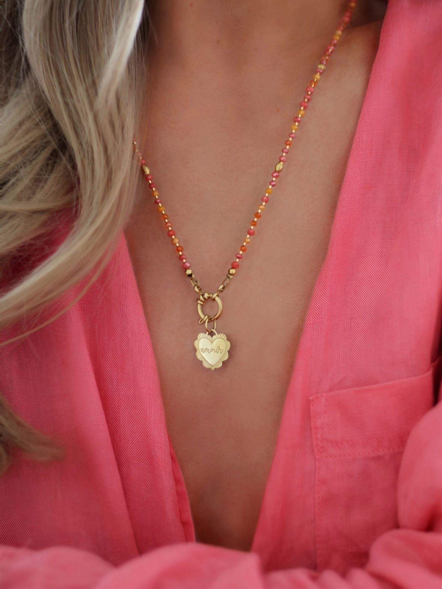 Ein goldener Anhänger AMOUR in Herzform aus Edelstahl. Flexibel an Halsketten und Ohrringe hängbar. Bunter Schmuck