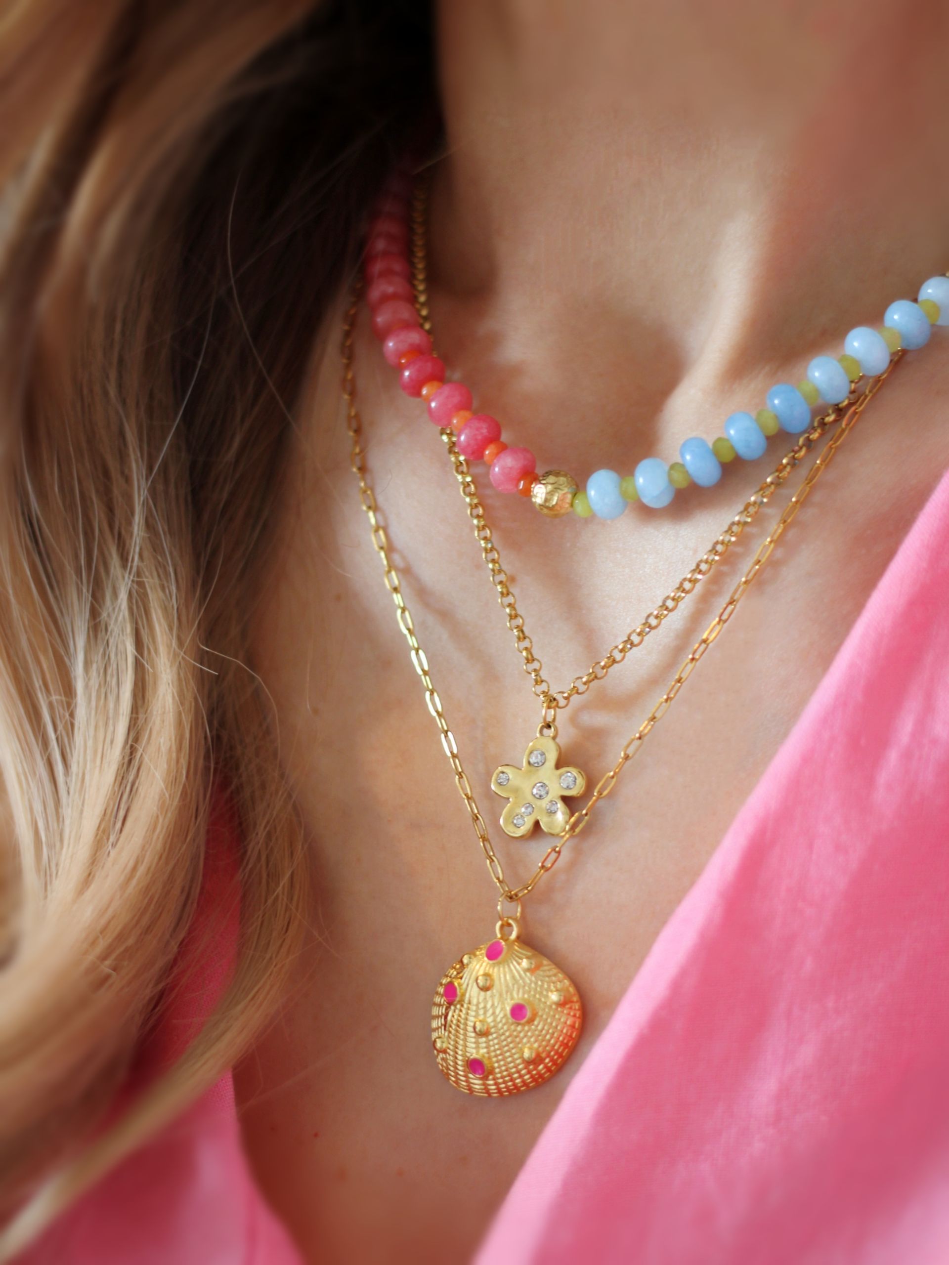 Nahaufnahme einer handgemachten, bunten Halskette aus Edelsteinperlen in den Farbtönen Blau, Grün, Rosa, Orange und Gold