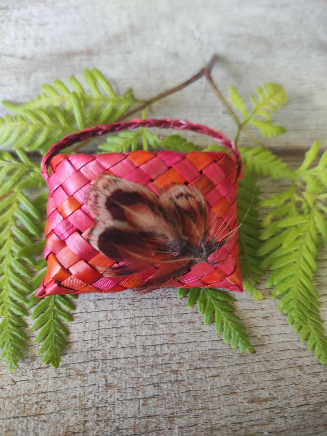 Orange/pink harakeke kete brooch with feathers