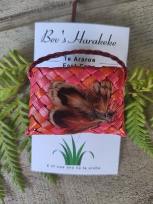 Orange/pink harakeke kete brooch with feathers