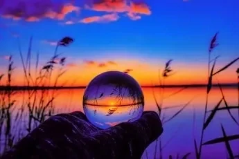 Boule de cristal devant crépuscule bleu et orange, les principes de la question voyance mail