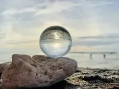 Boule de cristal sur rocher devant ciel bleu pâle, les principes de la voyance mail évolution de situation
