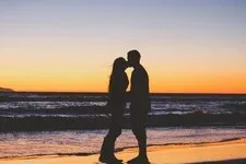 Couple qui s&#39;embrasse au soleil couchant, en bord de plage. Guidance par mail amour, offre spéciale été 2024, découvrez vos énergies de l&#39;été sur le plan amoureux !