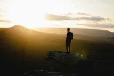 Que faire après une voyance par mail ? Individu en pleine nature, introspection face au soleil levant, décor montagnard