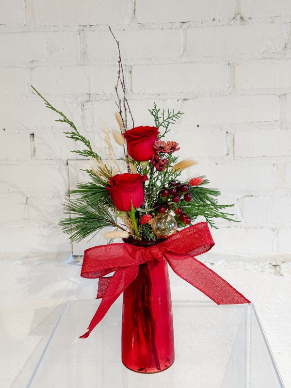 Bohemian Christmas flower arrangement with red roses, evergreen greenery, branches and a red ribbon