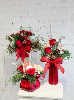 Boho-ho-ho rustic Christmas floral arrangements in red vases with roses, greenery and natural accents