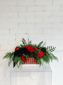 Checked In For Christmas centrepiece with red roses, evergreen greenery and a red checked container