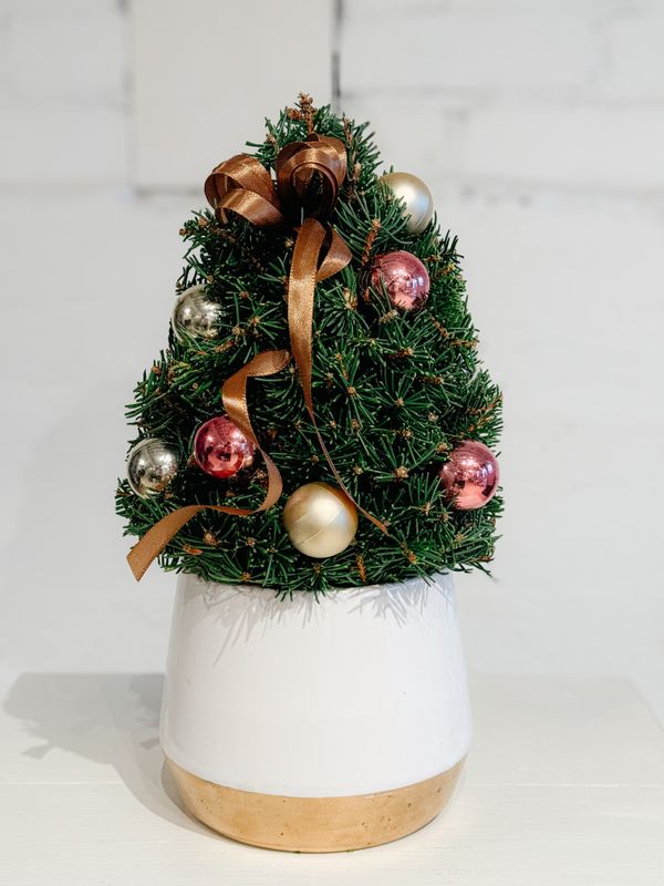 Tabletop Christmas tree made with evergreen greenery and decorated with gold and copper holiday ornaments