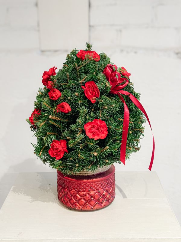 Mini Christmas tree floral arrangement with red roses, carnations and fresh greenery in a festive red pot