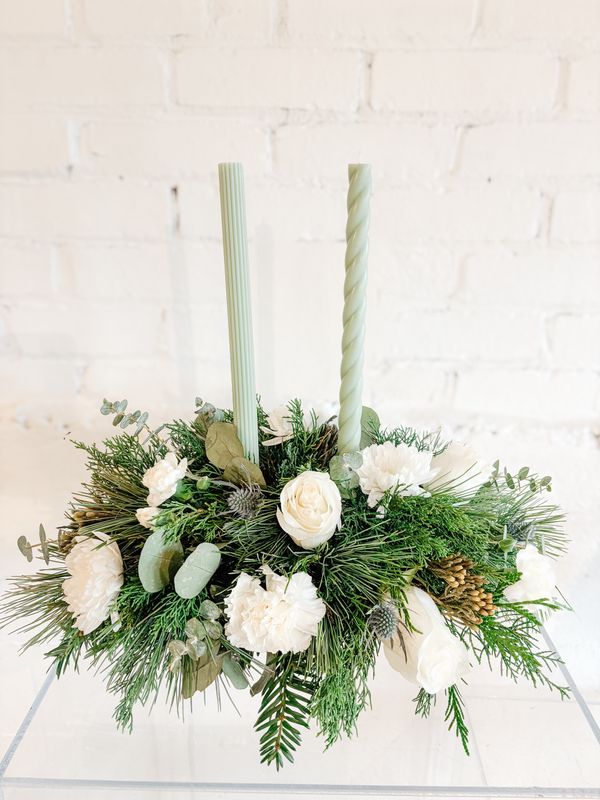 Traditional white Christmas centrepiece with taper candles, white flowers and evergreen greenery