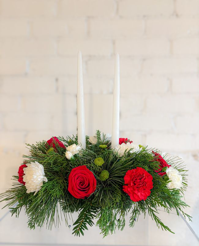 Medium traditional Christmas floral centrepiece with two white candles, red roses and white blooms