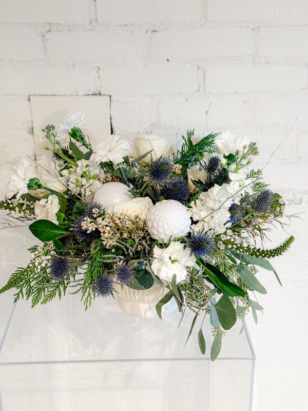 Close-up of blue thistle, white blooms and silver dollar eucalyptus in a Christmas flower arrangement