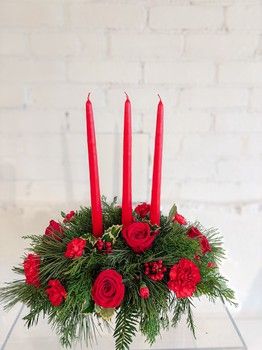 Large red Christmas centrepiece with three taper candles, red roses, carnations and fresh evergreen greenery