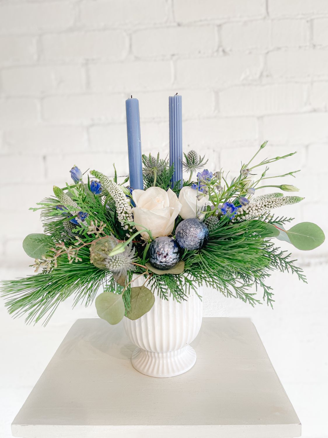 Coastal Candlelight Christmas centrepiece with white roses, blue candles, thistle and evergreen greenery