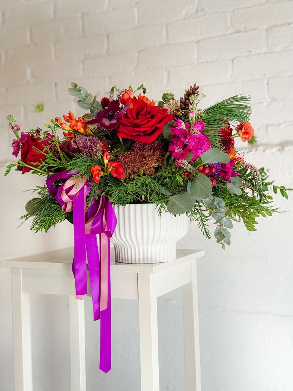 Large colourful holiday bouquet with red roses, bright pink flowers, greenery and purple ribbon