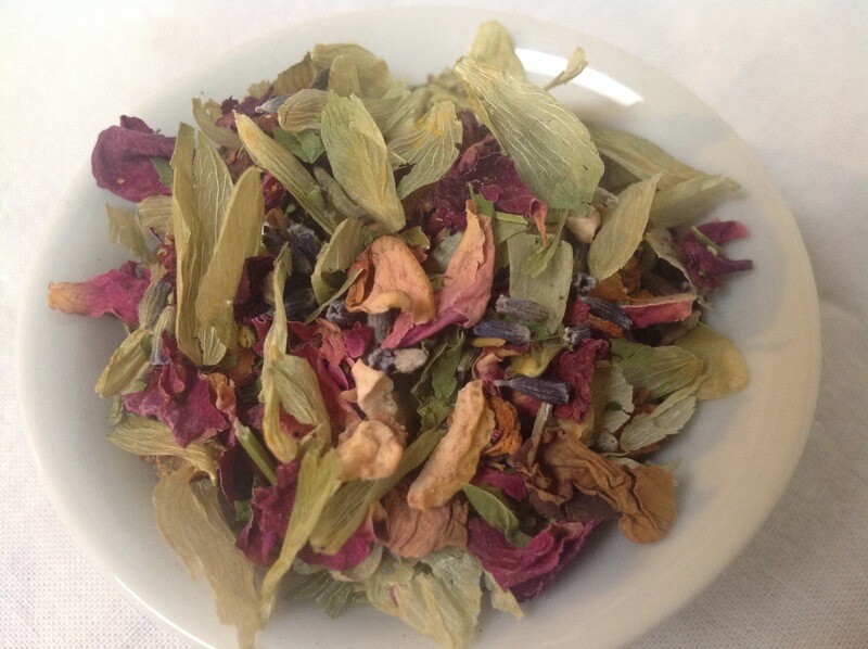 A small white bowl full of a blend of hops and rose petals and lavender and hawthorn berries and some green herbs.