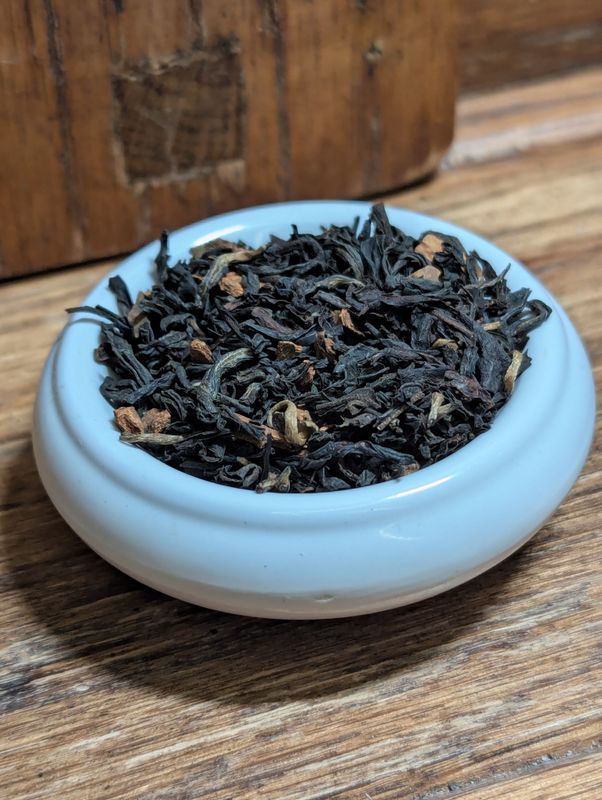 A small white bowl full of a blend of black teas and bits of cinnamon.