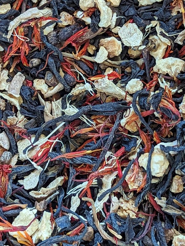 A zoomed in close image of safflower threads, bits of ginger and cinnamon, decorticated cardamom, and orange peel.