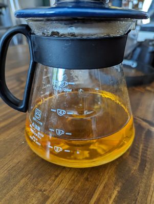 A glass pourover container filled almost to the 3 cup line with a golden orange liquid.