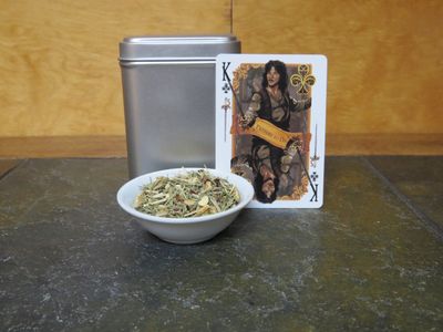 A small white bowl full of a blend of lemongrass, rosehips, orange peel, and cinnamon sits in front of a tin and card.