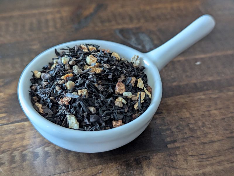 A small handled white bowl full of a blend of black tea, cardamom, and lemon peel - lightly dusted with vanilla.