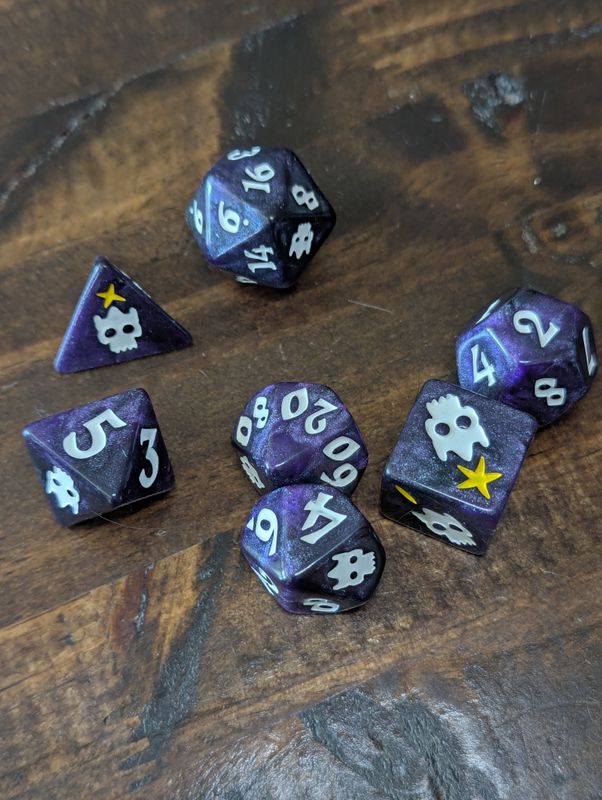 A full set of purple swirly glittery dice with skulls on them haphazardly scattered on a wooden table