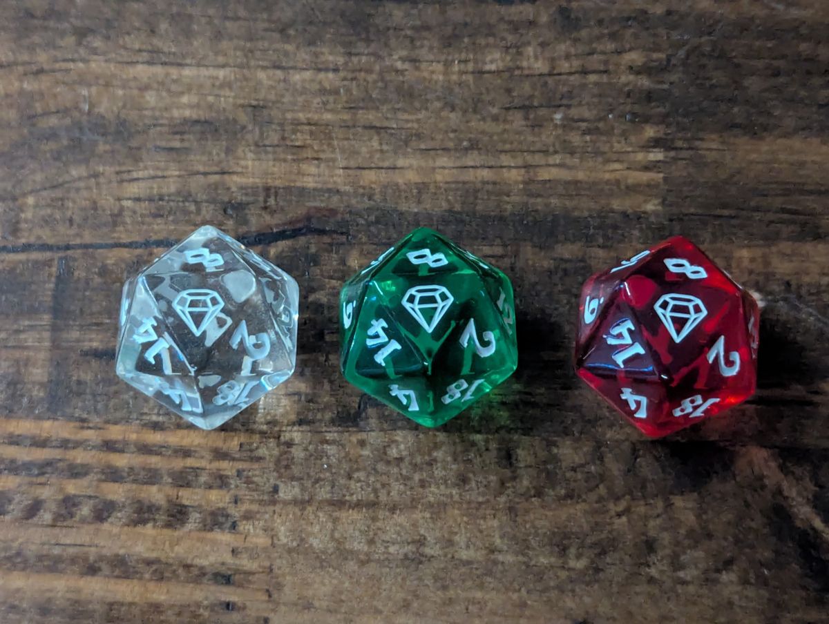 Three transluscent d20s, clear - red - and green, with jewels instead of the number 20.