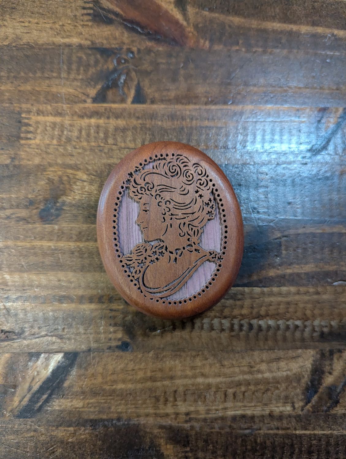 Top of a small wooden cameo carved music box.