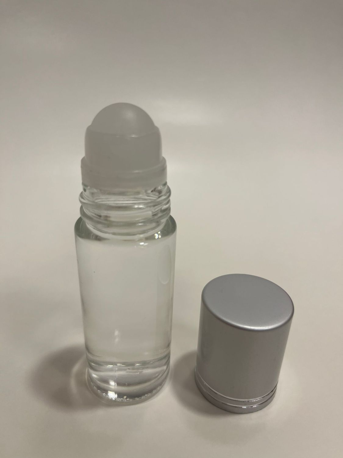 Picture of a clear glass roll-on bottle and a shiny silver cap.