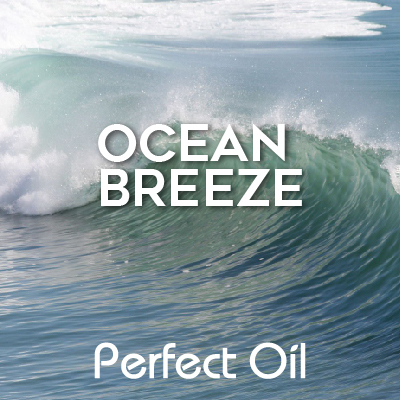 Picture showing a curling ocean wave moving left under a cloudy sky with the words ocean breeze and Perfect Oil in white on top of the image itself. 