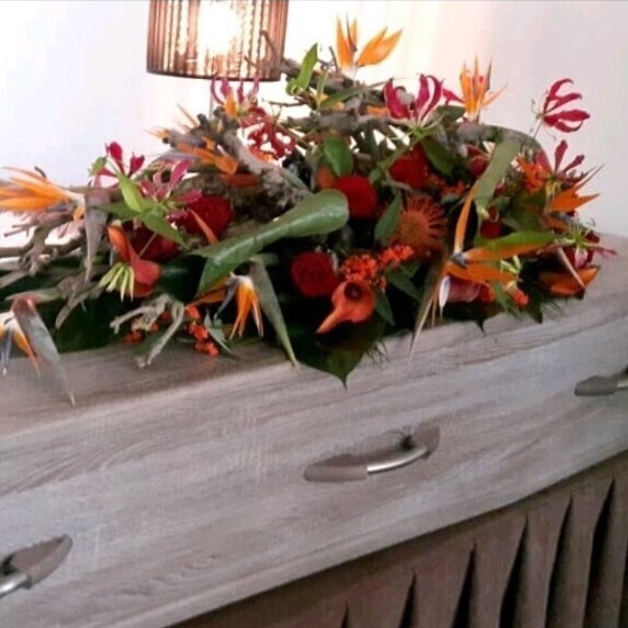 Rouwbloemstuk kistbedekking met natuurlijke stronk en exotische bloemen