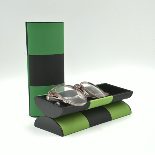 Zauberbrillenetui dunkelgrün-schwarz stehend, davor die andere Seite (hellgrün-schwarz) offen mit Brille darin