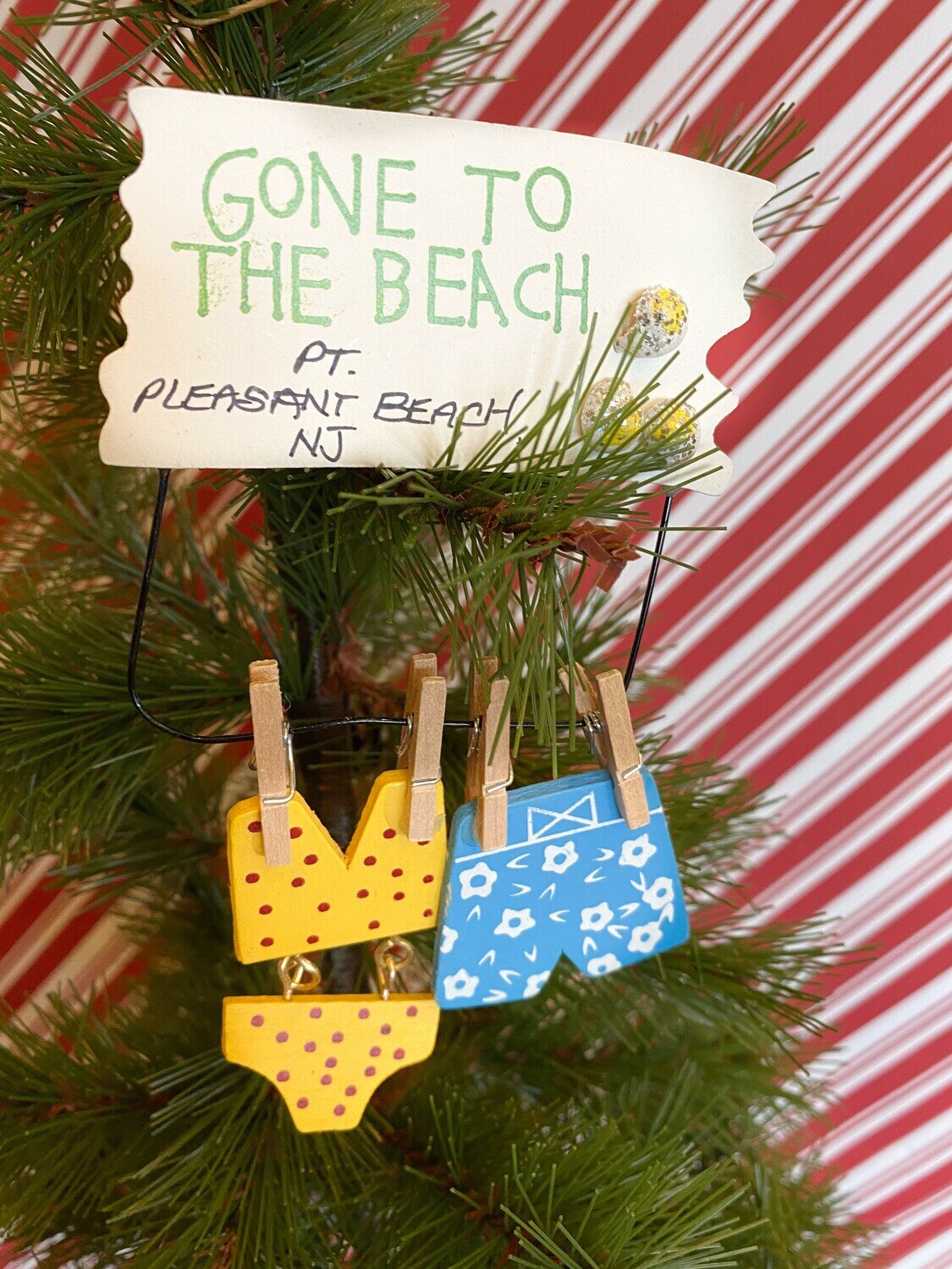 An ornament with a magnet on the back. It has a wood sign that says &quot;Gone to the Beach&quot; and &quot;Pt. Pleasant Beach, NJ&quot; above a yellow bikini with black polka dots and light blue swim shorts with white flowers hanging from clothes pins.