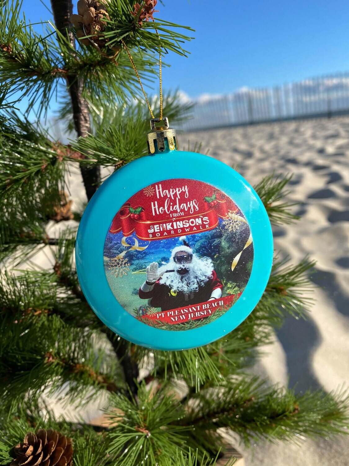 Aqua blue happy holidays ornament with a scuba diving Santa printed on one side