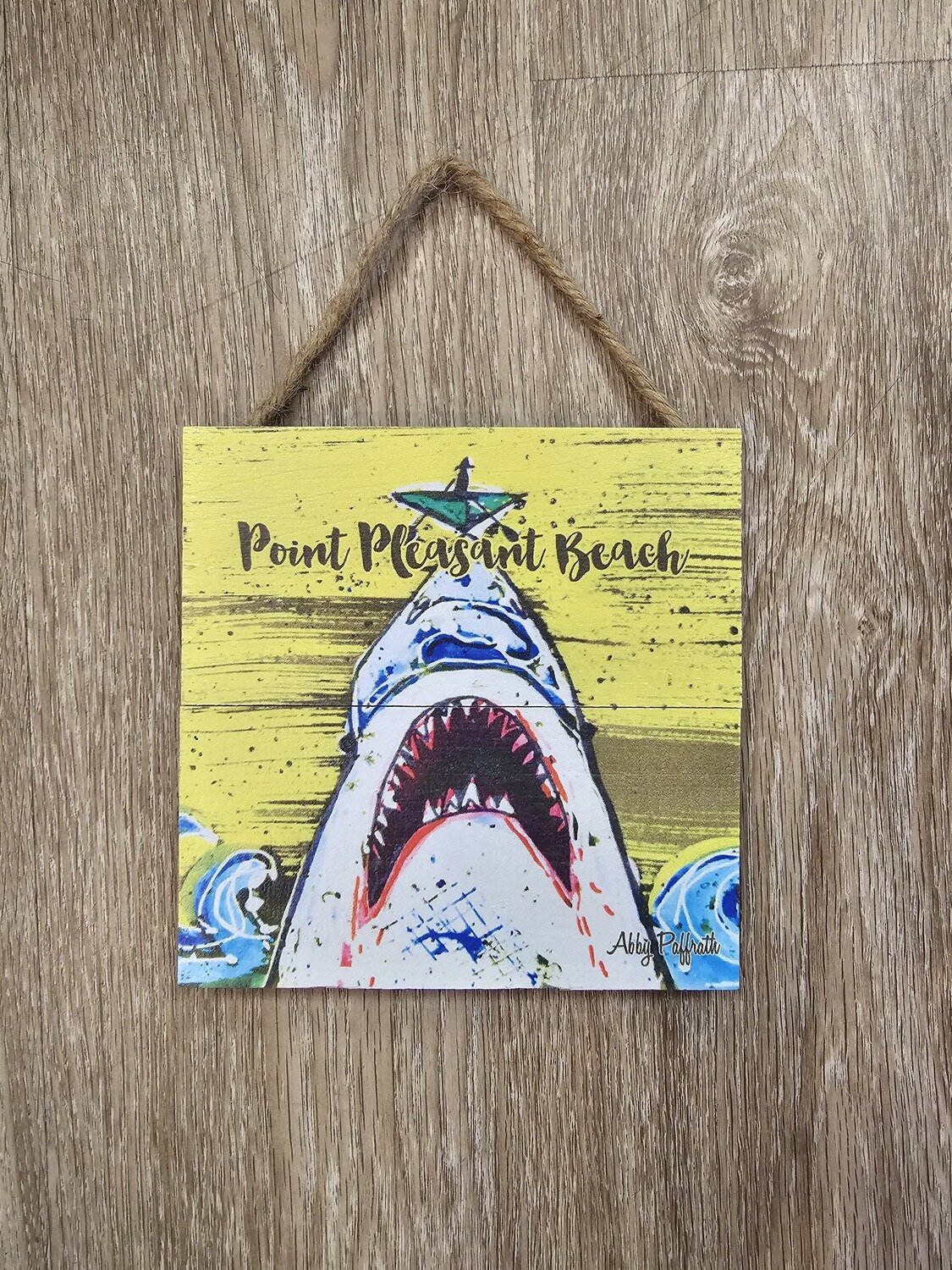 A square sign with a shark on a yellow background and the words Point Pleasant Beach
