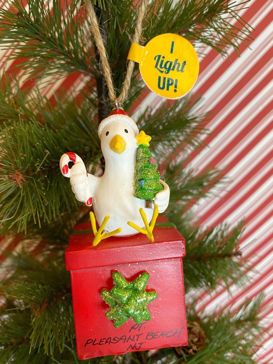 A Point Pleasant Beach ornament of a seagull wearing a Santa Claus hat sitting on a red present box with a green bow