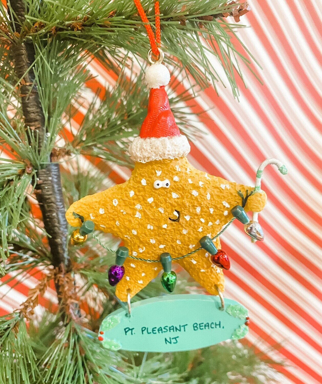 A starfish holding Christmas lights and wearing a Santa hat above a surfboard that says Point Pleasant Beach, NJ
