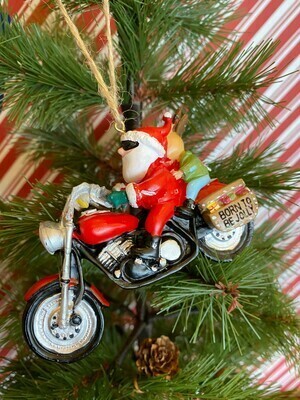 The reverse side of a Christmas tree ornament of Santa riding a red motorcycle with a reindeer passenger wearing sunglasses, a &quot;Born to Be Jolly&quot; inscription on the saddlebag, and &quot;Pt. Pleasant&quot; written on the bike, hanging on a pine tree branch.