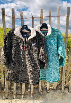 Two Puppie Love brand sherpa pullovers, one in brown and the other in green, hanging on a fence by the beach at Jenkinson&#39;s Boardwalk in Point Pleasant Beach, NJ 