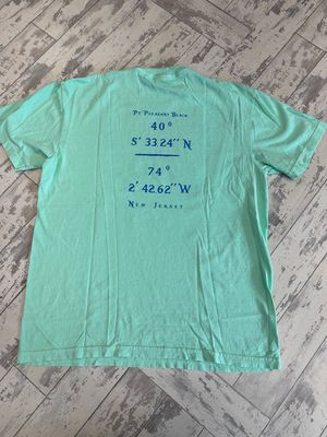 The back of a mint-green t-shirt displaying the coordinates &quot;40° 5&#39; 33.24&quot; N, 74° 2&#39; 42.62&quot; W&quot; in blue text, along with &quot;Point Pleasant Beach&quot; written above and &quot;New Jersey&quot; below.