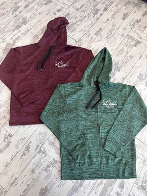Two full-zip hooded sweatshirts with &quot;Point Pleasant Beach&quot; embroidery, one in marbled maroon and the other in marbled olive, displayed on a rustic wooden floor.