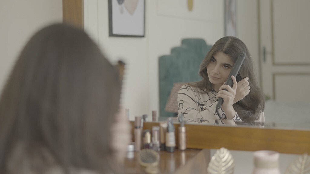 a woman sitting in front of the mirror brushing her hair