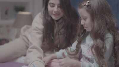 ام مع بنتها يرسمان معا على السرير 