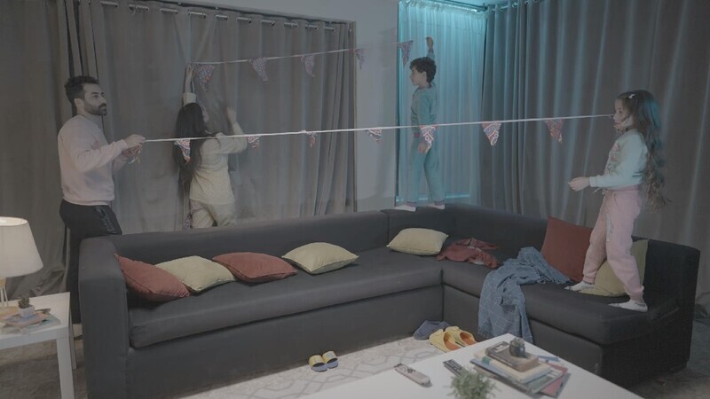 a family of four hanging the ramadan decoration in the living room