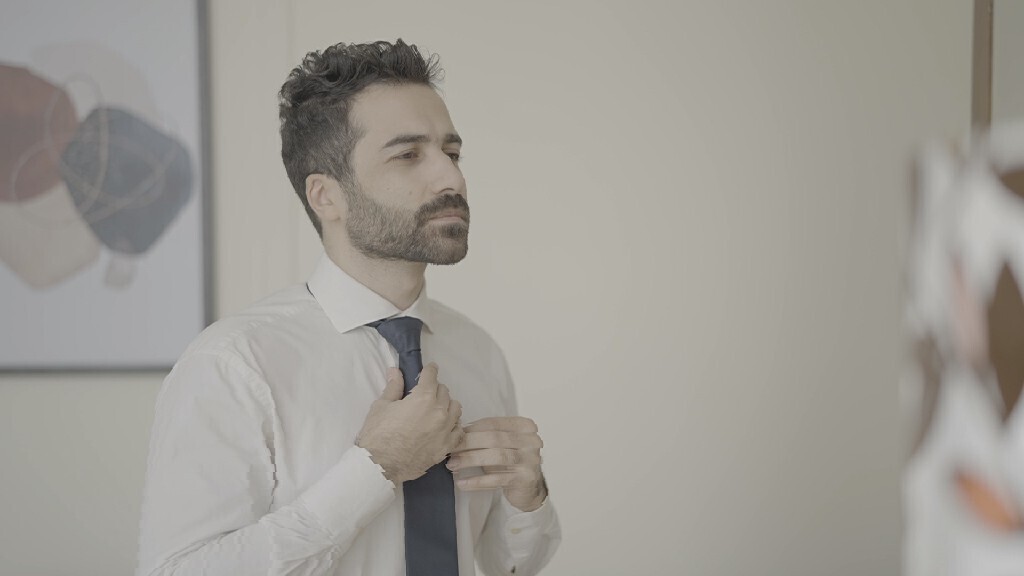 رجل يقف امام المرأة يرتدى سترة 