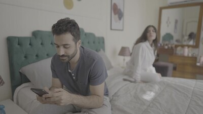 رجل يكتب على الهاتف اثناء وجود زوجته بجانبه 