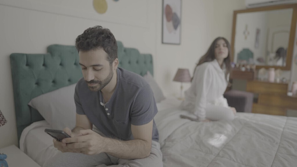 a man texting on the phone while her wife is beside him