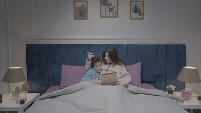 a woman reading a story to her son in bed